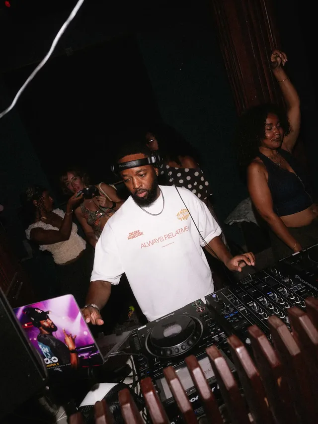 A DJ mixing while the crowd dances behind the booth.