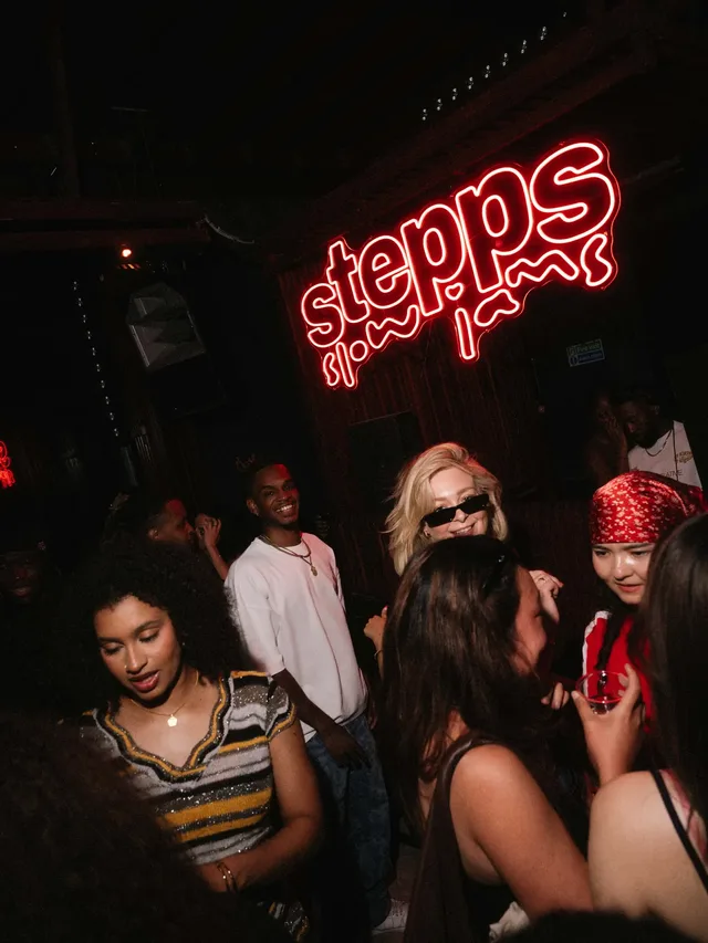 Friends dancing together in a dark room under the Stepps Slow Jams sign.
