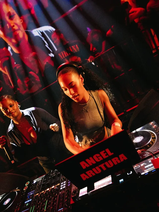 A DJ playing in warm red stage light.