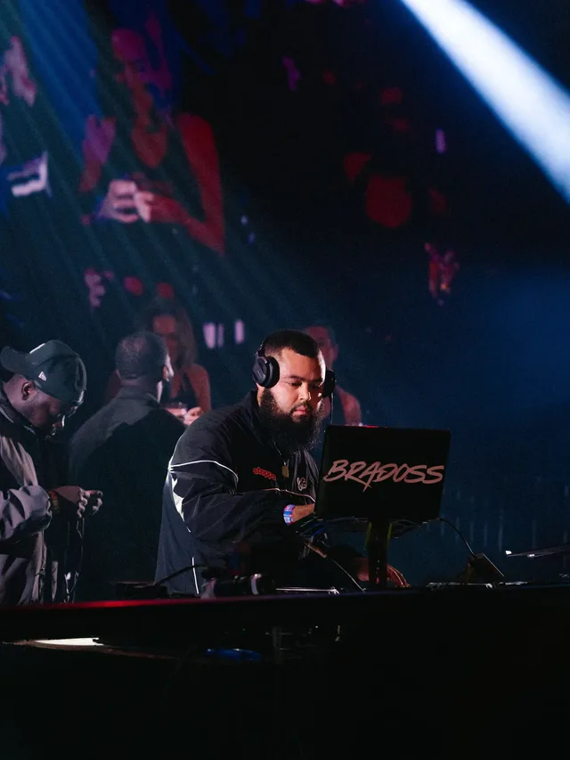 A DJ beneath a bright beam of blue stage light.