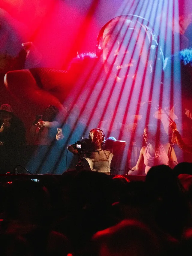 Hands raised towards the stage under red and blue lights.