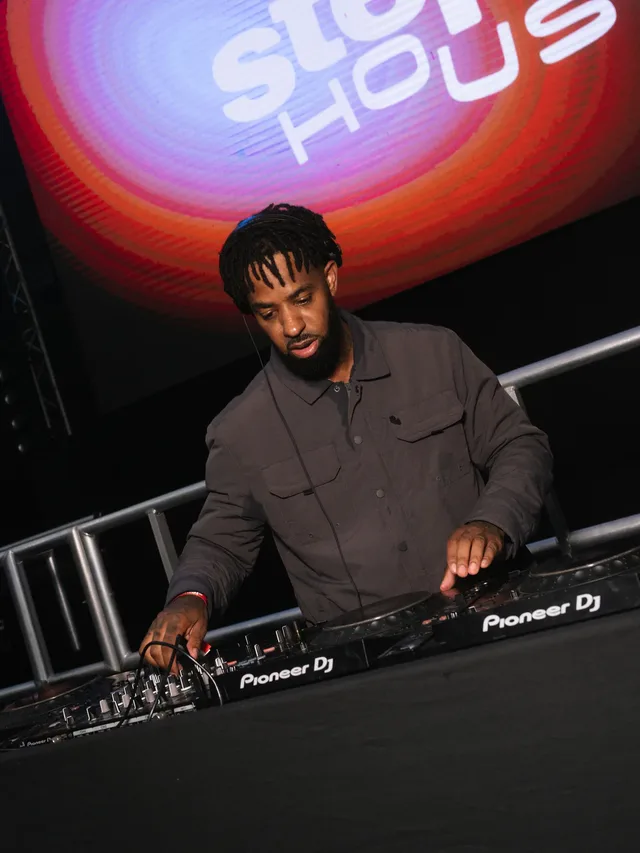 A DJ playing beneath the Stepps House screen.